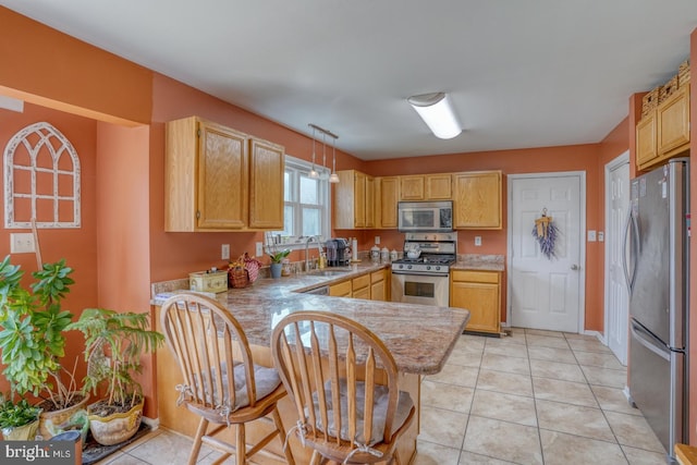 kitchen featuring a sink, appliances with stainless steel finishes, a peninsula, and light countertops