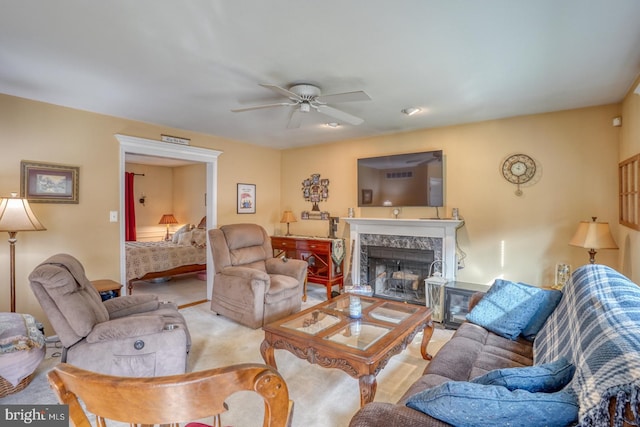 carpeted living room with ceiling fan and a premium fireplace