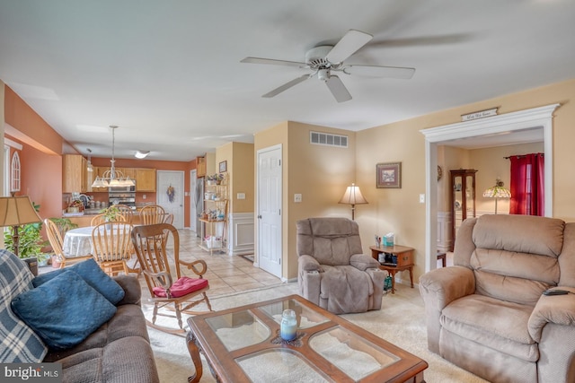 living area with light tile patterned flooring, visible vents, light colored carpet, and ceiling fan