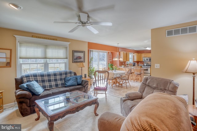 living area with ceiling fan, baseboards, visible vents, and light carpet