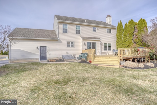 rear view of house featuring a wooden deck, a lawn, roof with shingles, and a chimney