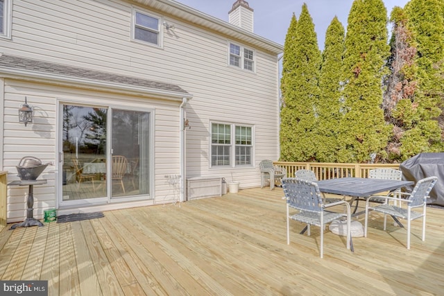 wooden terrace featuring area for grilling and outdoor dining space