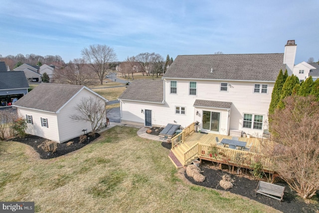 back of house with a wooden deck, a lawn, and a shingled roof