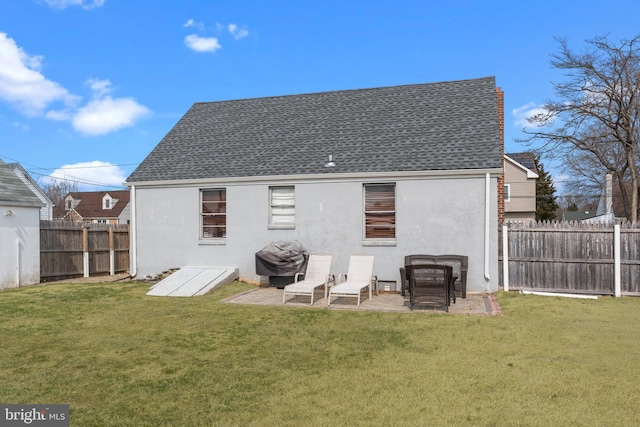 rear view of house with a yard, a fenced backyard, and stucco siding