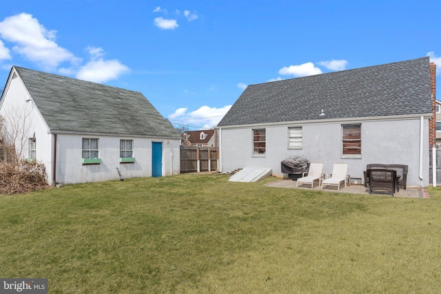 back of house with a shingled roof, a yard, fence, and stucco siding