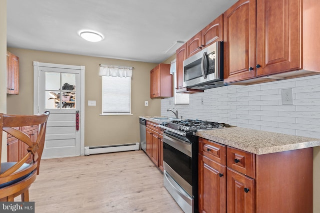 kitchen with light wood-style flooring, decorative backsplash, light countertops, appliances with stainless steel finishes, and baseboard heating