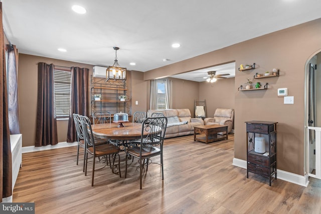 dining room featuring arched walkways, recessed lighting, baseboards, and wood finished floors