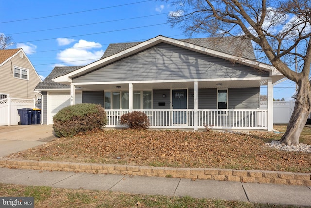 view of front of home with a porch, fence, roof with shingles, concrete driveway, and a garage