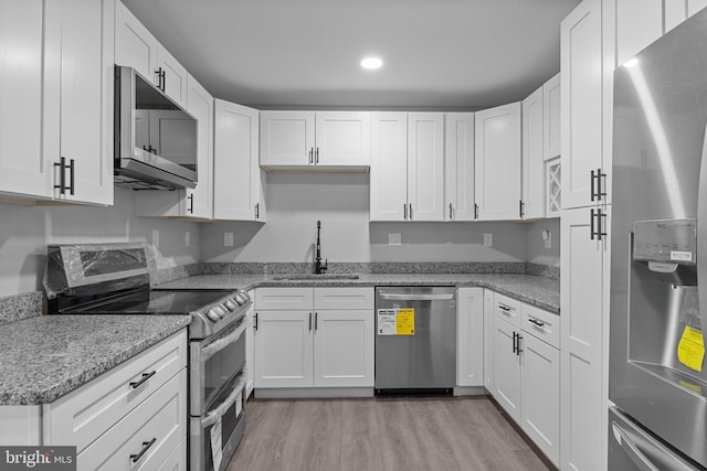 kitchen with white cabinets, stainless steel appliances, light wood-style floors, and a sink