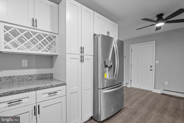 kitchen with white cabinets, stainless steel fridge with ice dispenser, a baseboard radiator, light stone countertops, and dark wood-style flooring