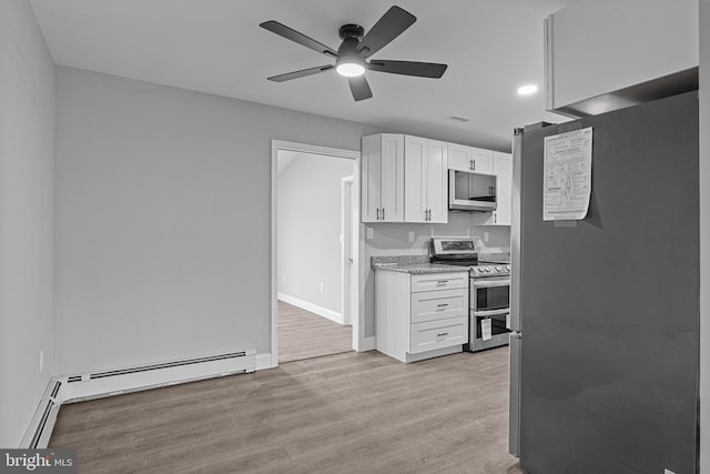 kitchen featuring stainless steel appliances, light wood-style floors, white cabinets, a baseboard radiator, and baseboards