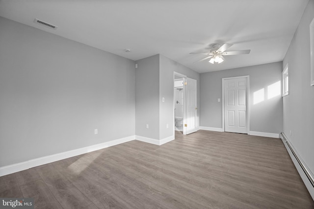 unfurnished room with visible vents, dark wood-type flooring, baseboards, and a baseboard radiator