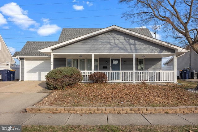 view of front facade featuring covered porch, concrete driveway, an attached garage, and a shingled roof