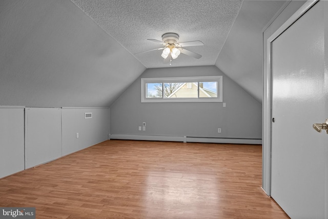 bonus room with ceiling fan, vaulted ceiling, light wood-type flooring, and a textured ceiling