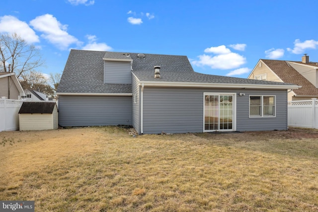 back of property with fence, a lawn, and a shingled roof