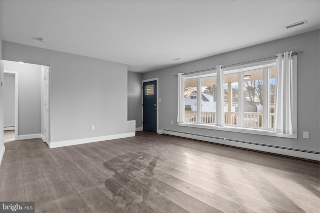 unfurnished living room featuring baseboards, visible vents, a baseboard radiator, dark wood finished floors, and baseboard heating