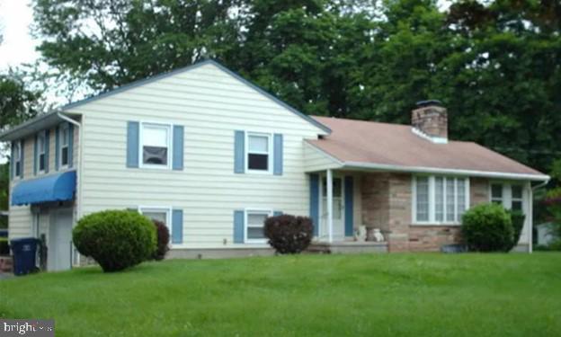 split level home featuring a front lawn and a chimney