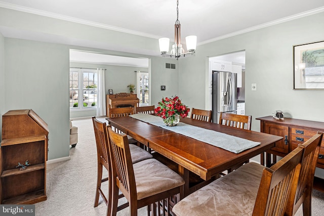 dining area with visible vents, crown molding, baseboards, light colored carpet, and a chandelier