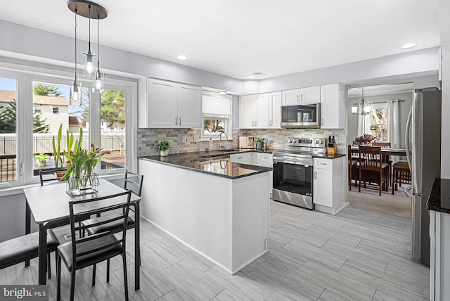 kitchen featuring decorative backsplash, white cabinets, appliances with stainless steel finishes, and a peninsula