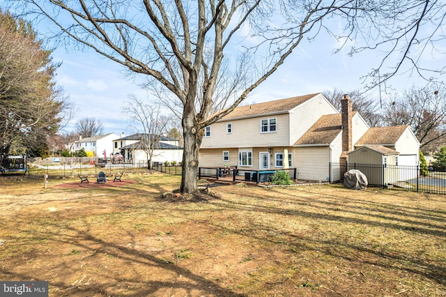 rear view of property with fence, a wooden deck, a lawn, a chimney, and an outbuilding