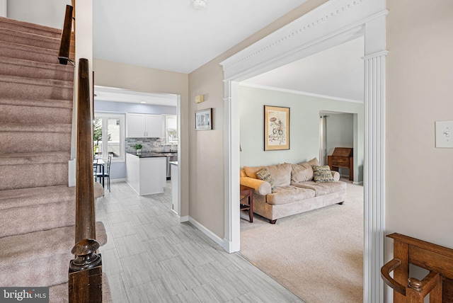 hallway featuring stairway, baseboards, light carpet, and ornamental molding