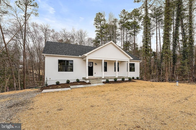 modern farmhouse with a porch and a shingled roof