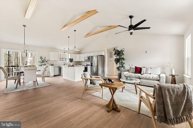 living area with ceiling fan, high vaulted ceiling, and light wood-style floors