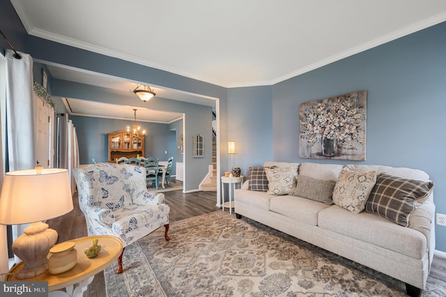 living area with stairway, wood finished floors, baseboards, crown molding, and a notable chandelier