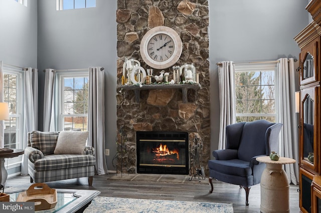 sitting room featuring wood finished floors, a fireplace, and a towering ceiling