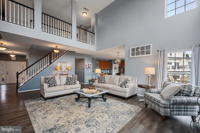 living room featuring stairway, wood finished floors, visible vents, and baseboards