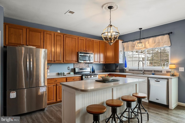 kitchen with a chandelier, light countertops, brown cabinets, appliances with stainless steel finishes, and a sink