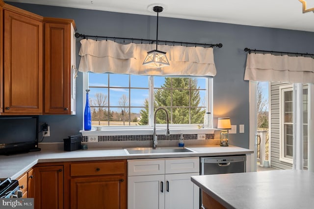 kitchen with light countertops, brown cabinets, appliances with stainless steel finishes, hanging light fixtures, and a sink