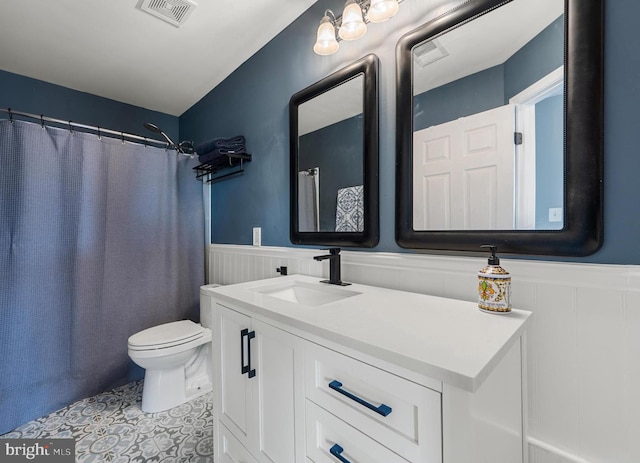 bathroom featuring vanity, visible vents, tile patterned flooring, wainscoting, and toilet