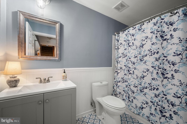 bathroom with visible vents, a wainscoted wall, toilet, a shower with curtain, and vanity