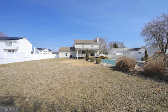 rear view of property with a residential view, a lawn, a fenced backyard, and a chimney