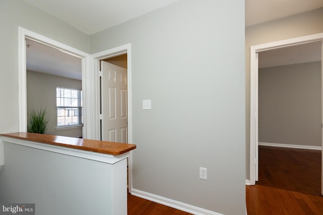 corridor featuring dark wood finished floors and baseboards