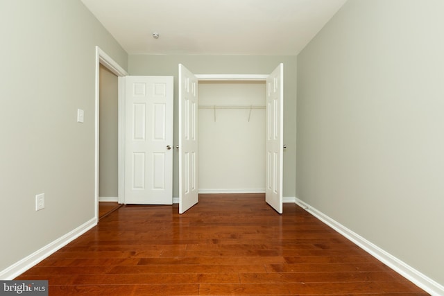 unfurnished bedroom featuring a closet, baseboards, and wood finished floors