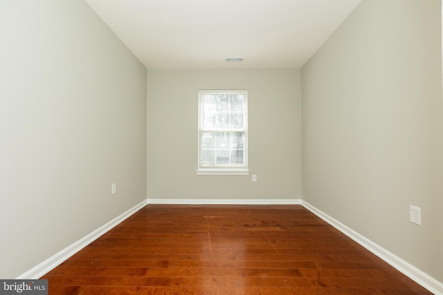 unfurnished room featuring wood finished floors, visible vents, and baseboards