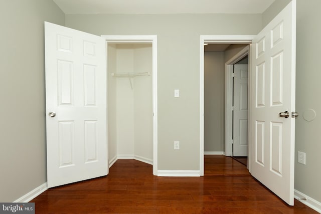 unfurnished bedroom with a closet, baseboards, and dark wood-style floors