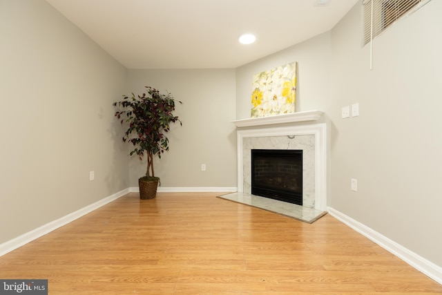 unfurnished living room featuring visible vents, baseboards, a fireplace, and light wood finished floors