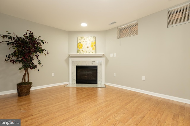 unfurnished living room featuring a fireplace, visible vents, baseboards, and light wood-type flooring