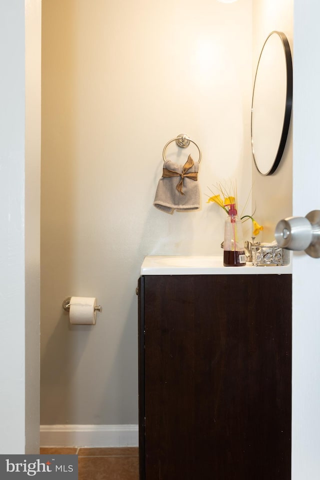 half bathroom featuring tile patterned flooring, vanity, and baseboards