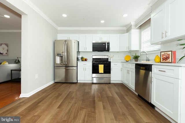 kitchen with appliances with stainless steel finishes, dark wood-style flooring, crown molding, and light countertops