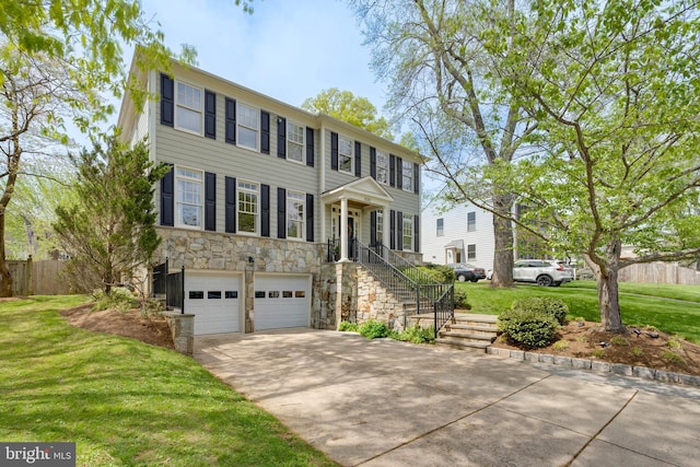 colonial house featuring fence, stone siding, a garage, a front yard, and concrete driveway