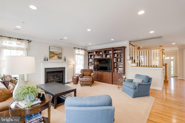 living room featuring crown molding, a fireplace with flush hearth, stairs, wood finished floors, and recessed lighting