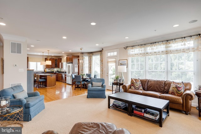 living room featuring crown molding, light wood finished floors, recessed lighting, and visible vents