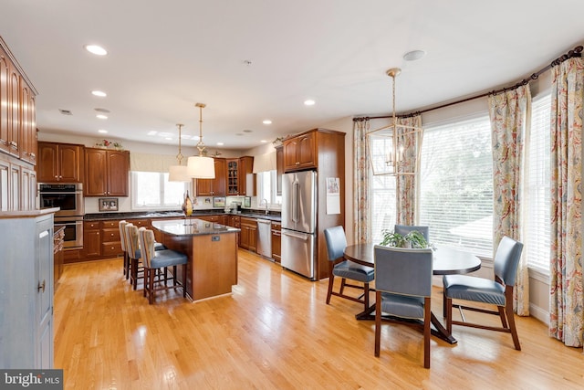 kitchen featuring dark countertops, a kitchen breakfast bar, brown cabinetry, stainless steel appliances, and a kitchen island