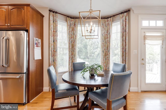 dining room featuring baseboards, light wood finished floors, and a chandelier