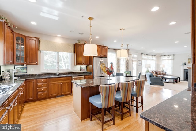 kitchen with a breakfast bar, a sink, plenty of natural light, stainless steel appliances, and open floor plan