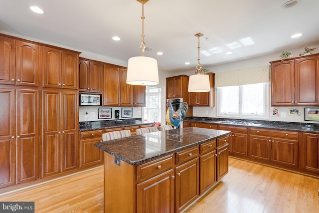 kitchen with plenty of natural light, light wood-type flooring, a kitchen island, and stainless steel appliances